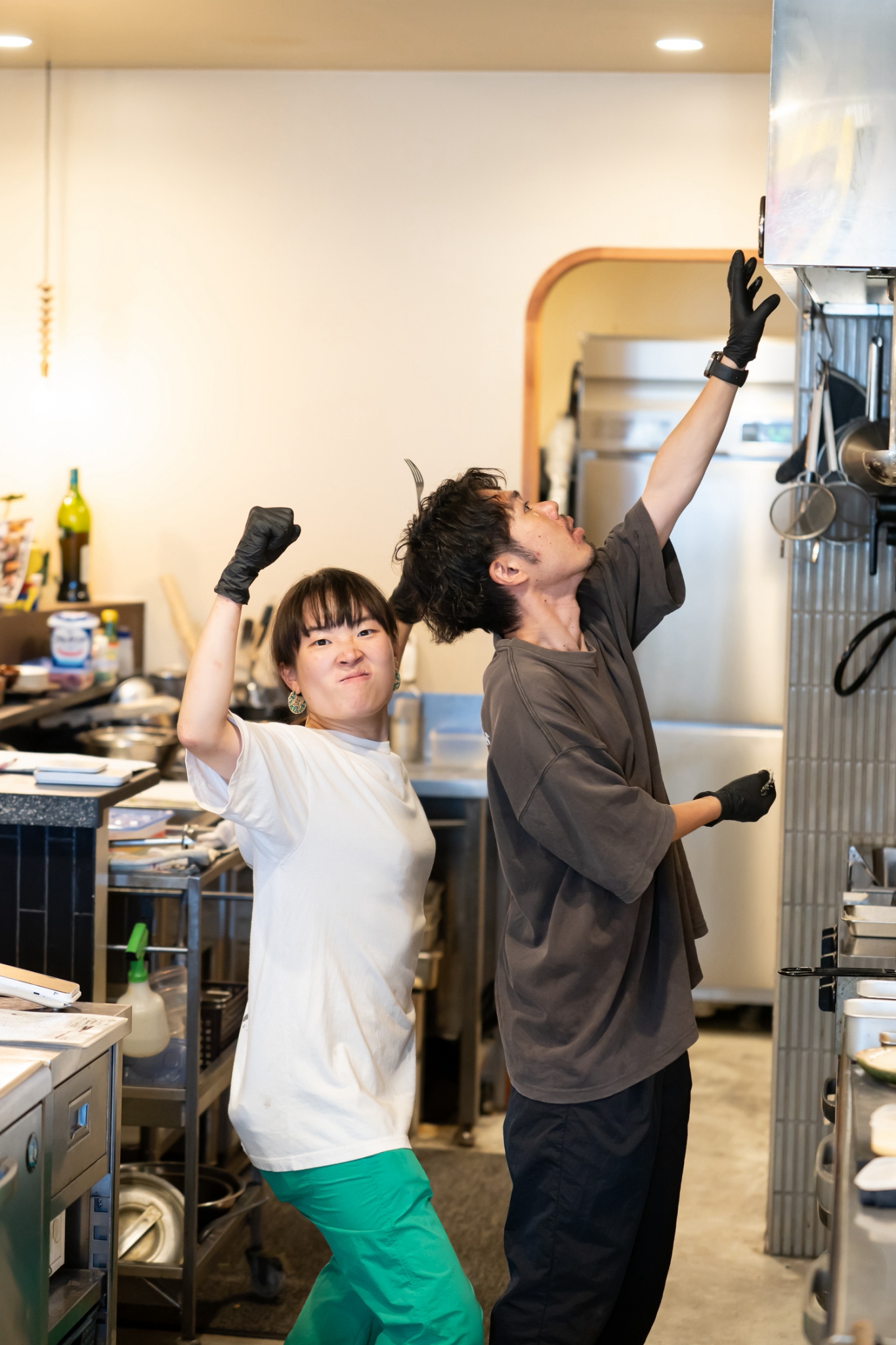 厨房で息の合ったポーズを見せる小粋酒場 ゲロッパ!のスタッフ2人