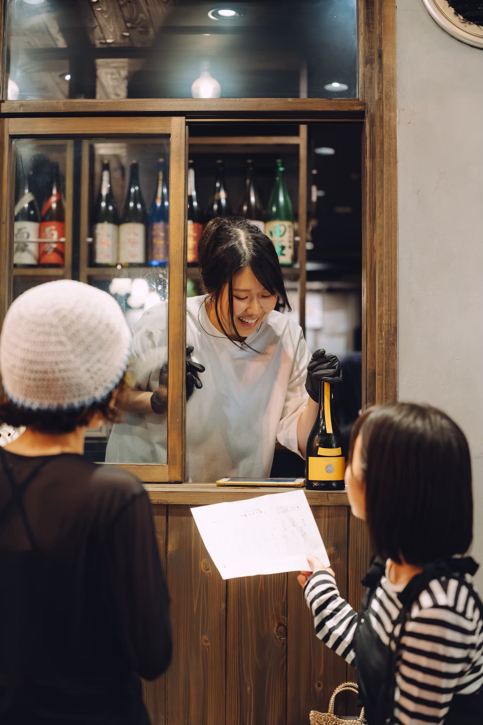 お酒を手渡しながら微笑む炭焼きと日本酒 炉端ヒトイキ。のスタッフ