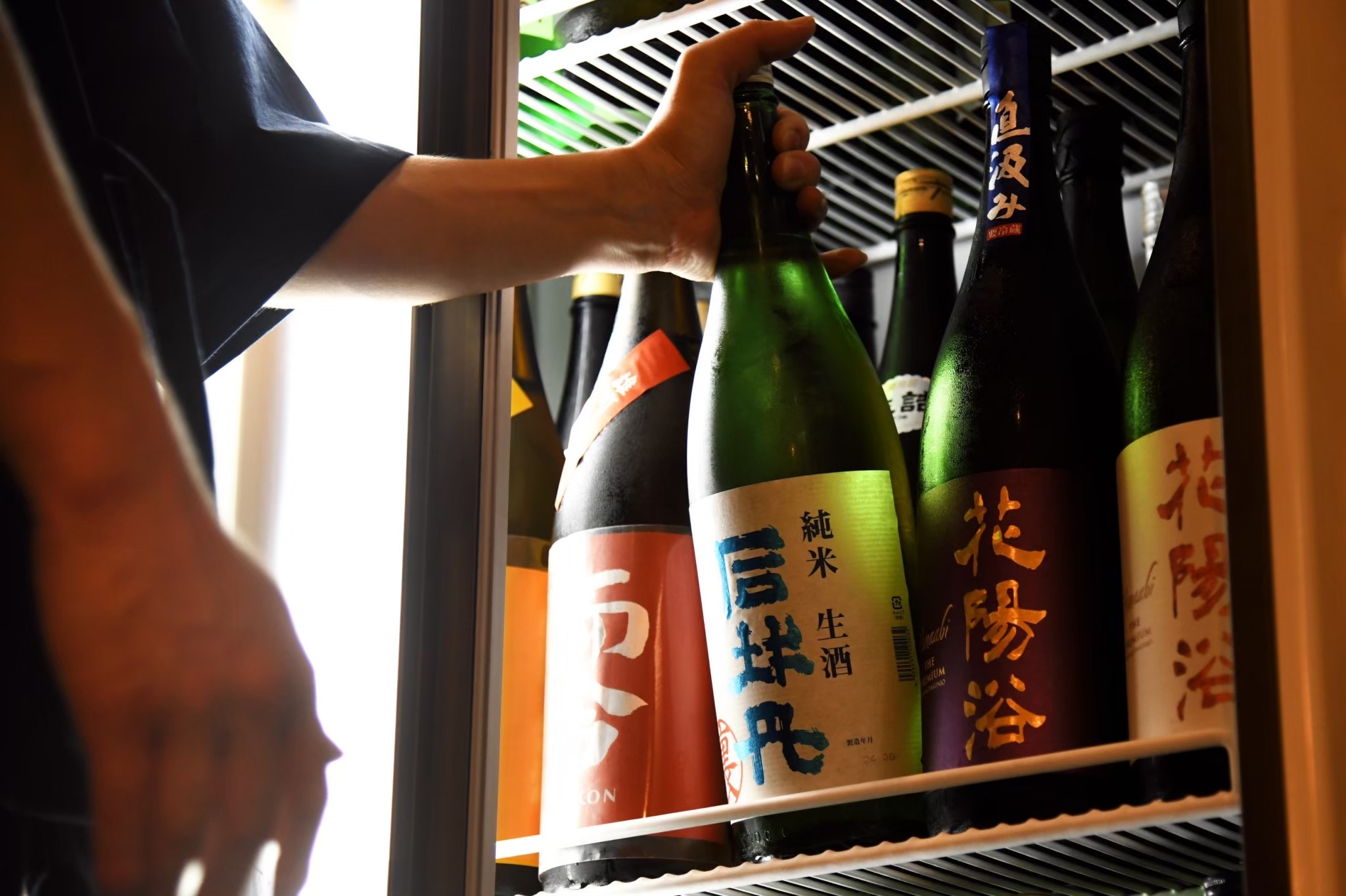 冷蔵庫から日本酒の一升瓶を取り出すスタッフの手元